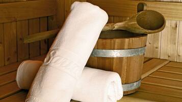 Una sauna de madera con un cubo de metal y una toalla enrollada.