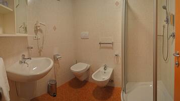 A bathroom with a sink, toilet, bidet, and shower.