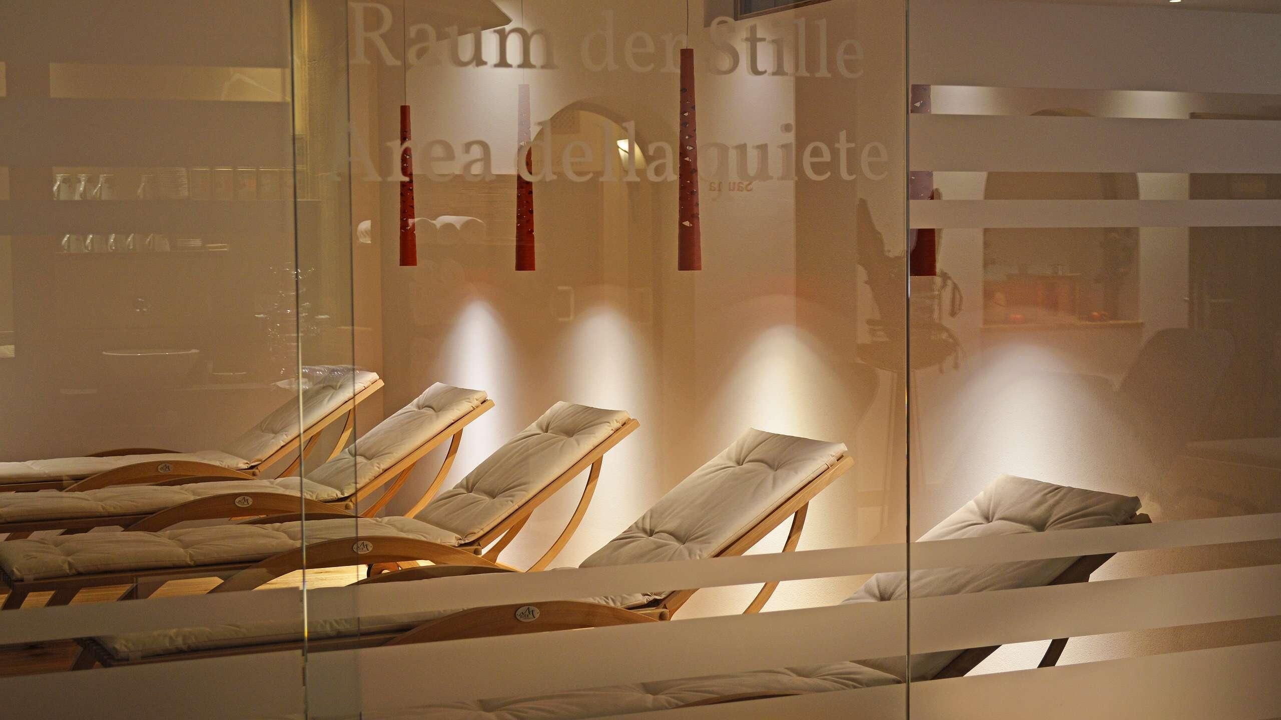 A spa room with sun loungers and a glass wall with text.