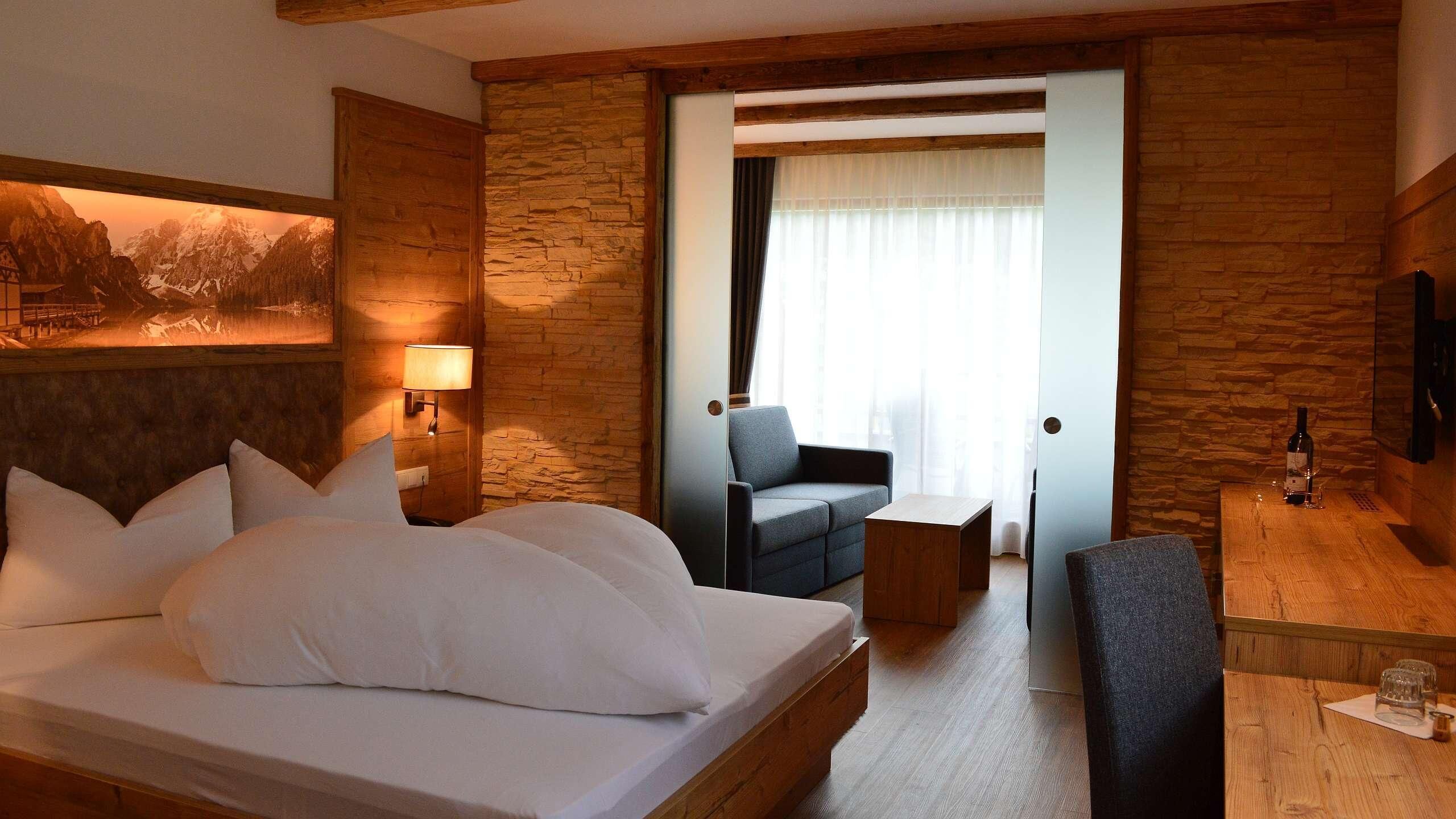 Una habitación de hotel con una cama grande, un escritorio, una silla y un cuadro en la pared.