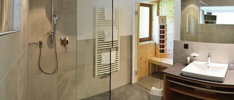 A modern bathroom with a glass-enclosed shower, a wooden vanity with a sink, and a mirror.