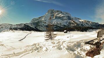 Un paysage enneigé avec une montagne, un banc en bois et une petite cabane.