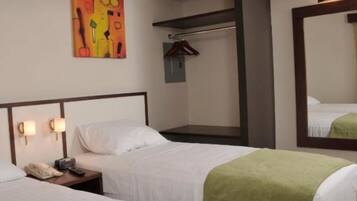 Een hotelkamer met twee bedden, een nachtkastje met een telefoon, een spiegel aan de muur en een kleurrijk abstract schilderij.