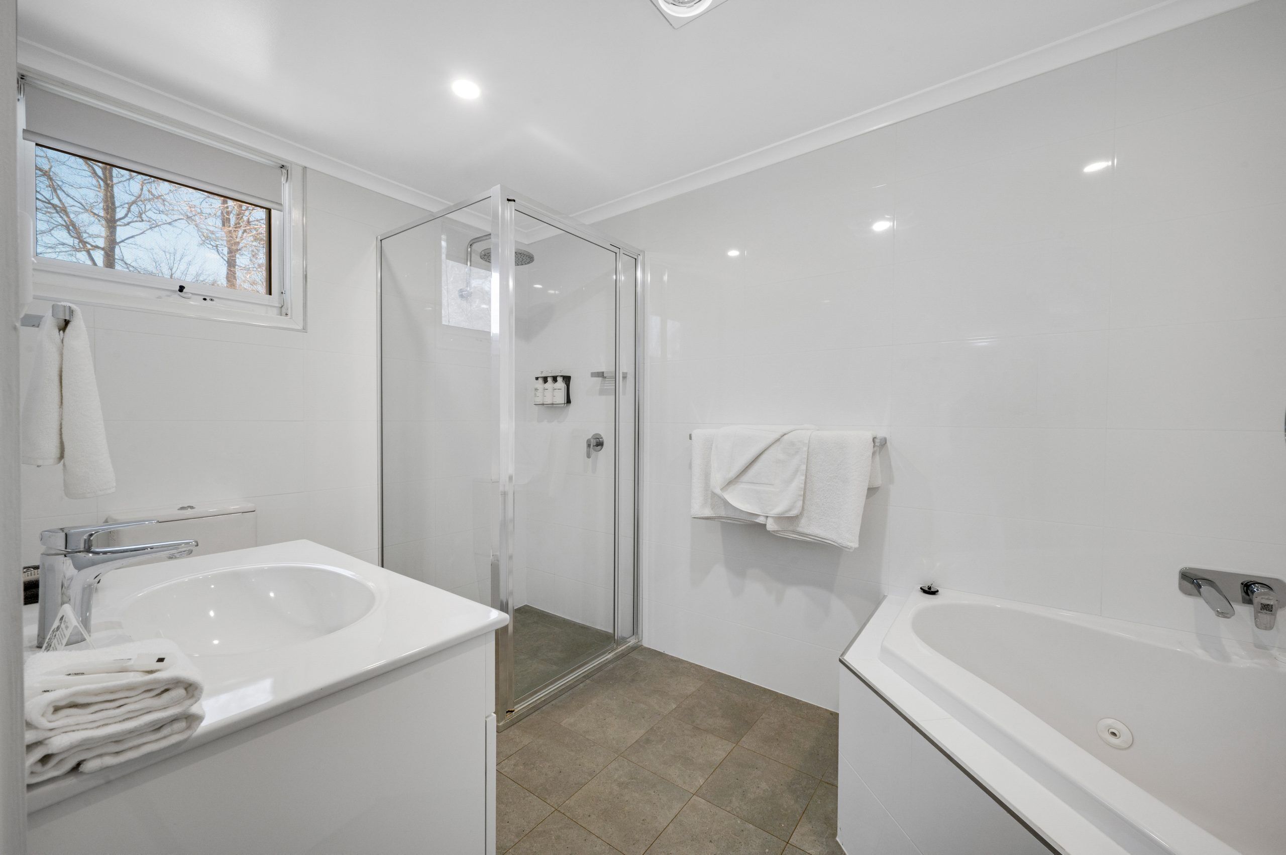 Un baño moderno con ducha de vidrio, una bañera grande y un lavabo.