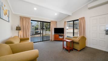 A room with a TV, two sofas, a small table, and a sliding glass door to the outside.