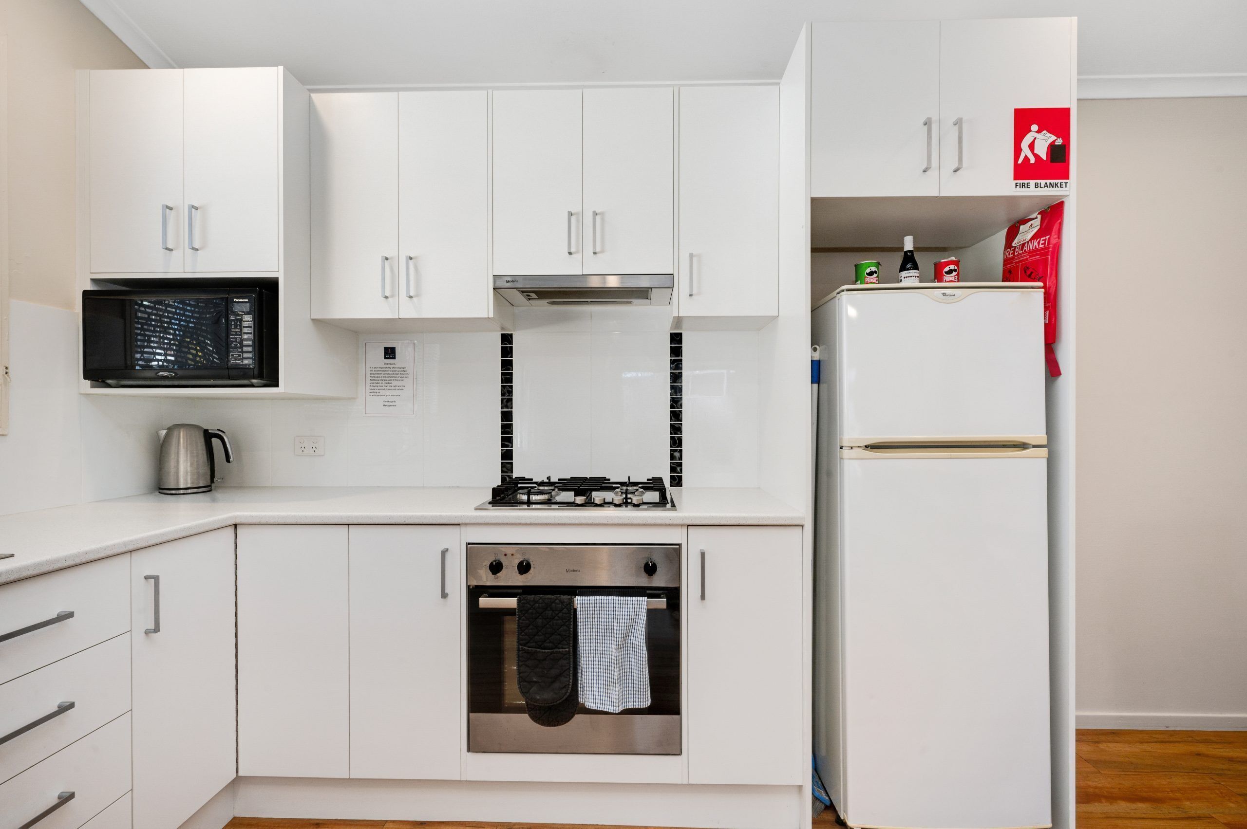 A modern kitchen with white cabinets, a microwave, a stove, and a refrigerator.