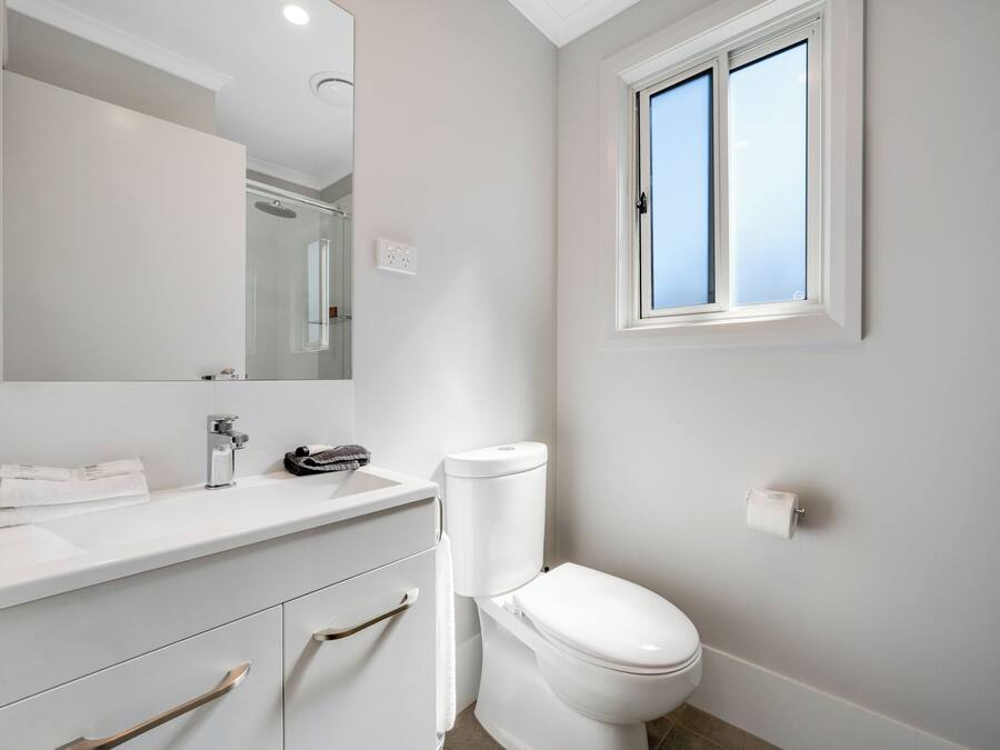 A modern bathroom with a white sink, mirror, and toilet.