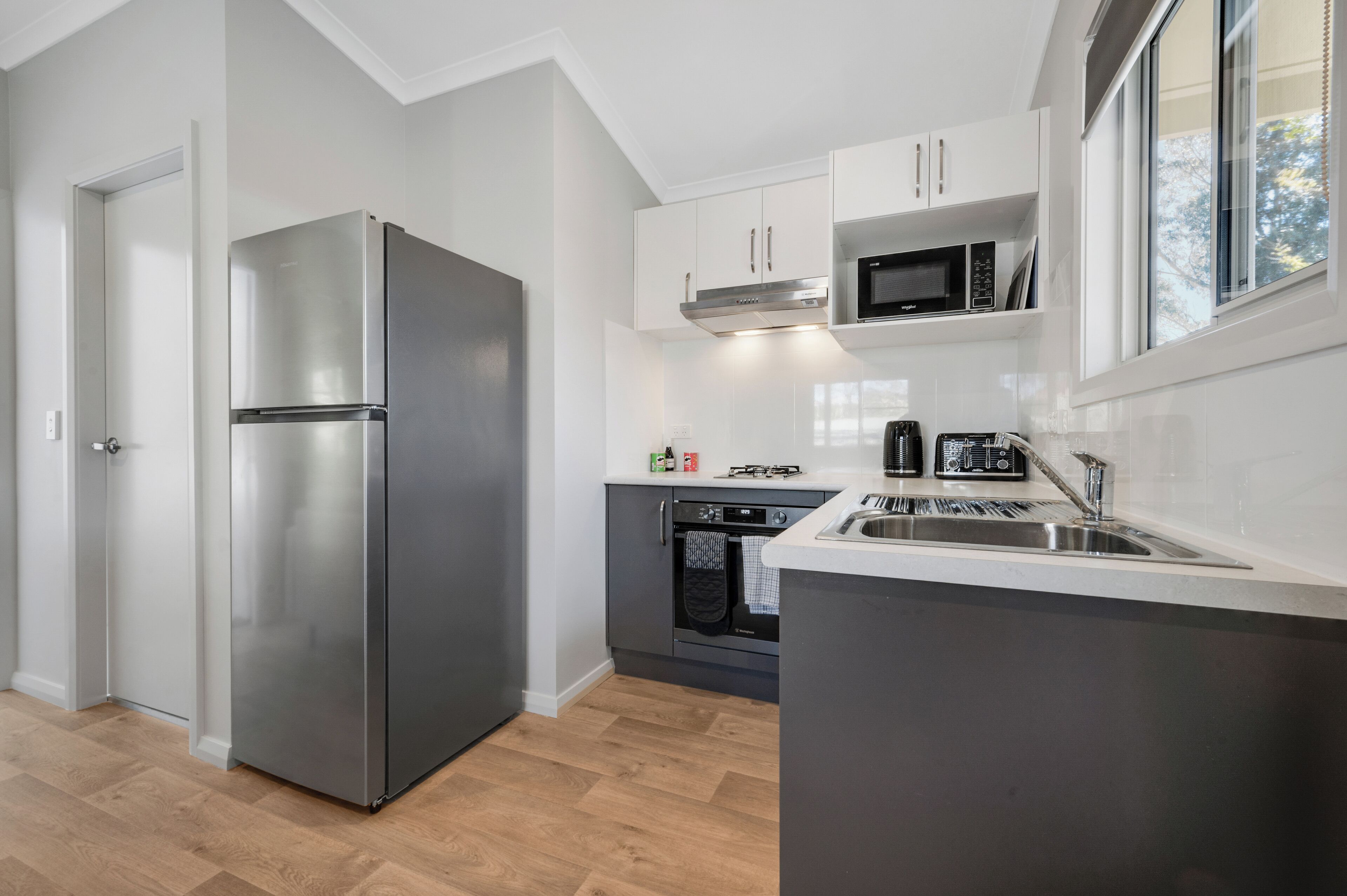 A modern kitchen with a stainless steel refrigerator, built-in oven, microwave, and sink.