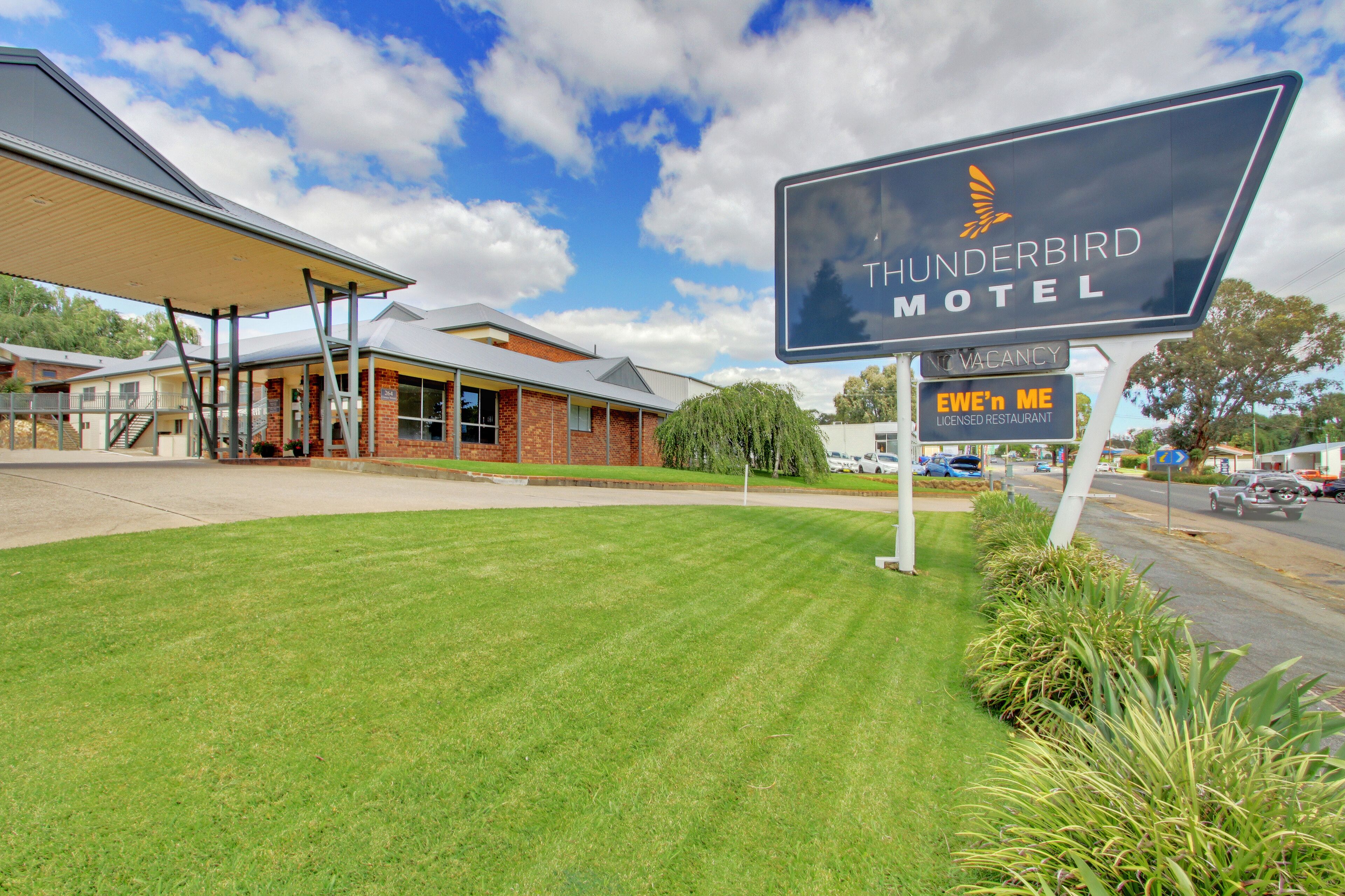 A motel sign with a logo, a vacancy sign, and a restaurant sign.