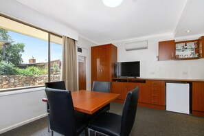 A compact kitchen with a dining area, a TV, and a refrigerator. - Thunderbird Motel (Yass)