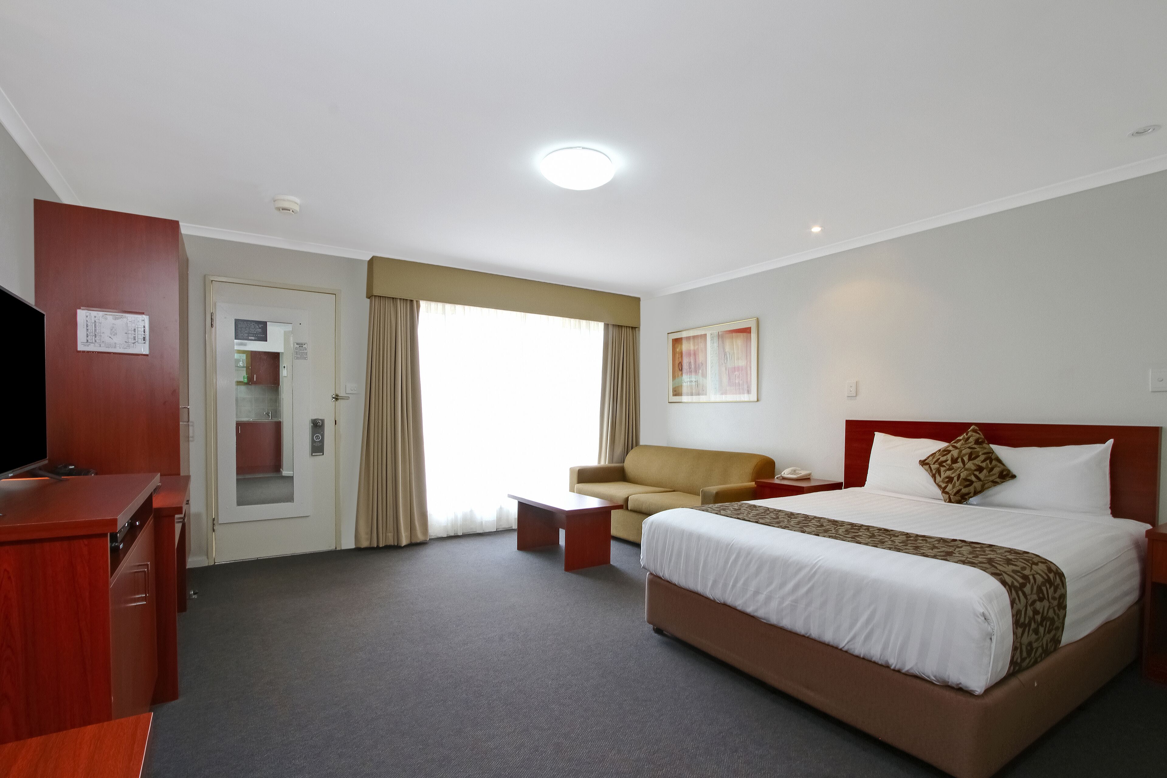 Una habitación de hotel con cama, sofá, escritorio y televisión.