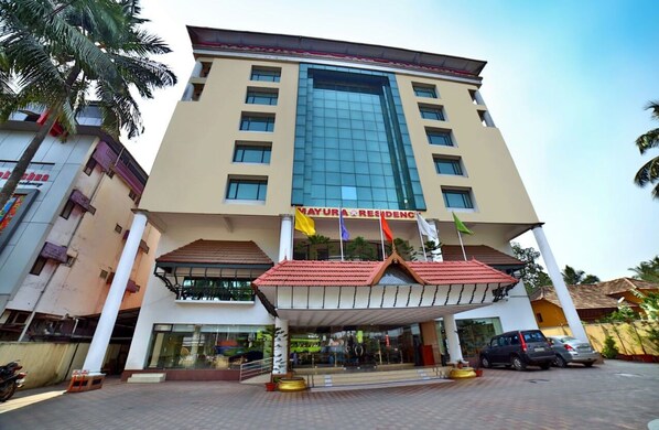 A multi-story hotel with a prominent entrance, a glass facade, and a red-tiled roof.