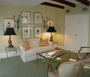 A living room with a white sofa, two side tables with lamps, a glass coffee table, and a chair. - The Stephen Williams House (Savannah)