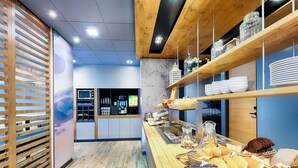 Un comptoir de petit-déjeuner avec divers pâtisseries et pains, des murs recouverts de lambris en bois, et un four à micro-ondes en arrière-plan.