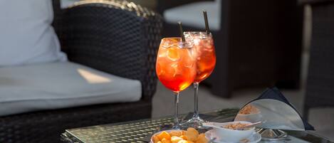 A table with two drinks, a bowl of snacks, and a menu.