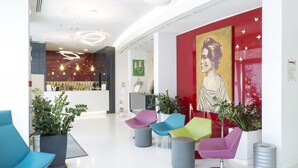Un lobby moderno con sillas coloridas, un mostrador de recepción y un cuadro grande en la pared.