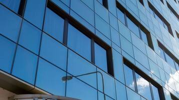 Un hôtel moderne, avec une façade en verre réfléchissant et une enseigne « HÔTEL » bien visible au-dessus de l’entrée.
