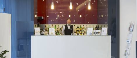 Eine moderne Bar mit Barkeeper, einer gut sortierten Bar und einem außergewöhnlichen Wanddesign mit hängenden Leuchten.