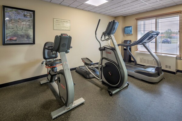 A gym with stationary bikes, a treadmill, and a wall map.