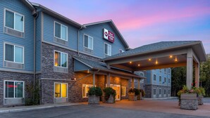 A Best Western Plus hotel with a stone facade, multiple windows, and a covered entrance area with potted plants. - Best Western Plus Chena River Lodge (Fairbanks)