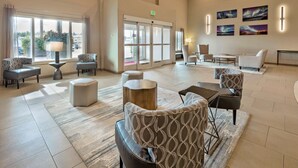 A spacious lobby with a seating area, a reception desk, and a large window with a view of the outside. - Best Western Plus Chena River Lodge (Fairbanks)
