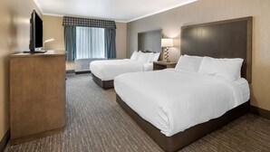 A hotel room with two beds, a TV, a desk, and a window with curtains. - Best Western Plus Chena River Lodge (Fairbanks)
