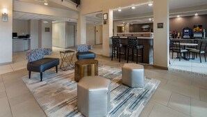 A modern lobby with a bar area, seating, and a kitchen in the background. - Best Western Plus Chena River Lodge (Fairbanks)