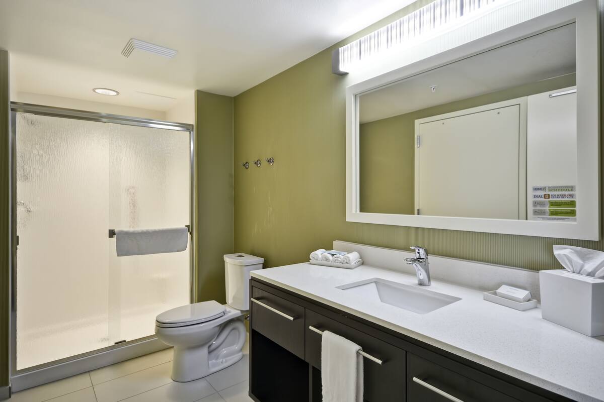 A modern bathroom with a shower, toilet, sink, and vanity.