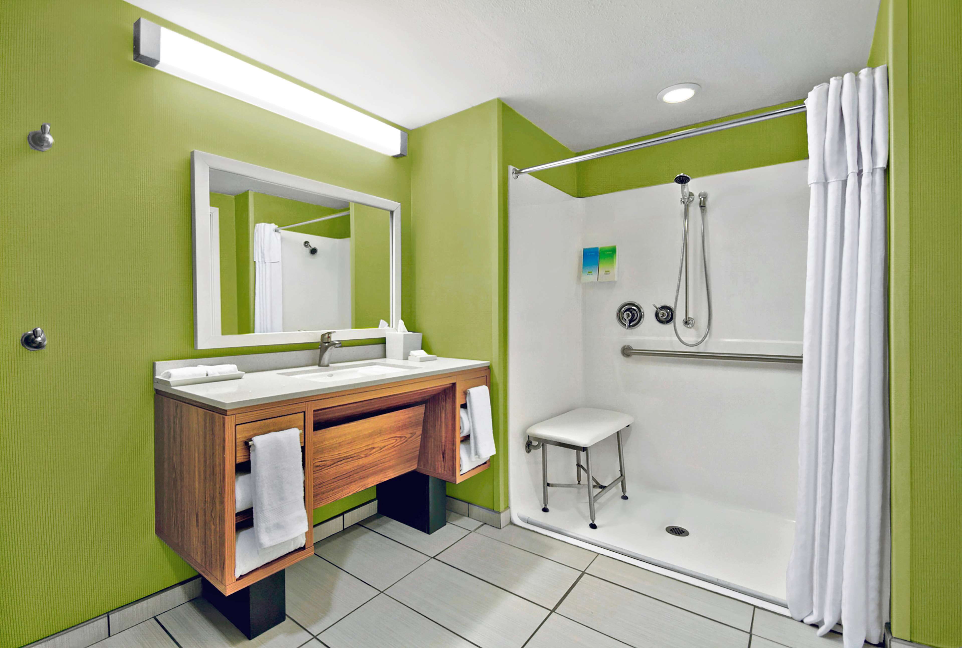 A bathroom with a wooden vanity, a white sink, a mirror, and a walk-in shower with a glass door.