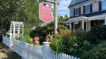 Una valla blanca de piquetes, un letrero de madera del Palmer House Inn y un edificio con un porche.