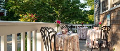 An outdoor patio with tables and chairs, surrounded by greenery.