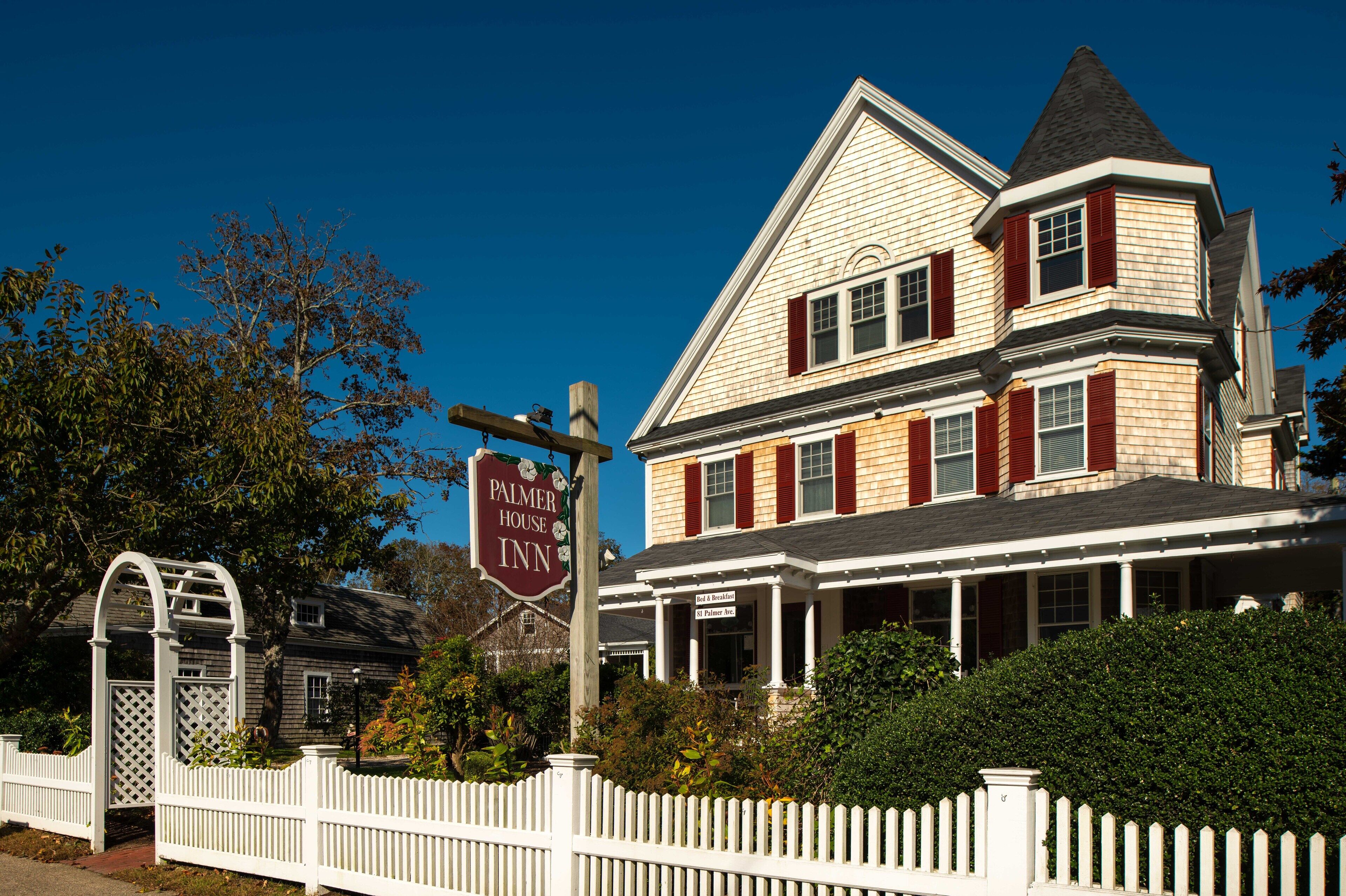 Een tweelaags huis met een veranda, een bordje met Palmer House Inn en een witte picket fence.