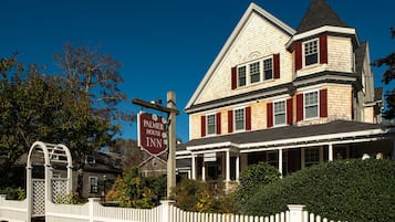 Een tweelaags huis met een veranda, een bordje met Palmer House Inn en een witte picket fence.