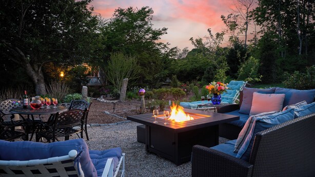 An outdoor patio with a fire table, seating, and a table set for a meal.