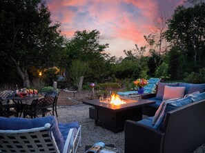 An outdoor patio with a fire table, seating, and a table set for a meal. - The Palmer House Inn (Falmouth)