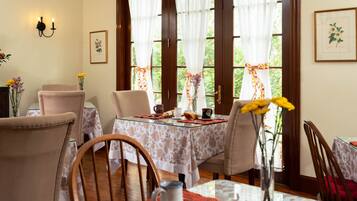Comedor con mesa de vidrio, mantel floreado y sillas.