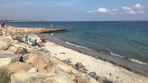 A rocky beach with people relaxing and fishing.