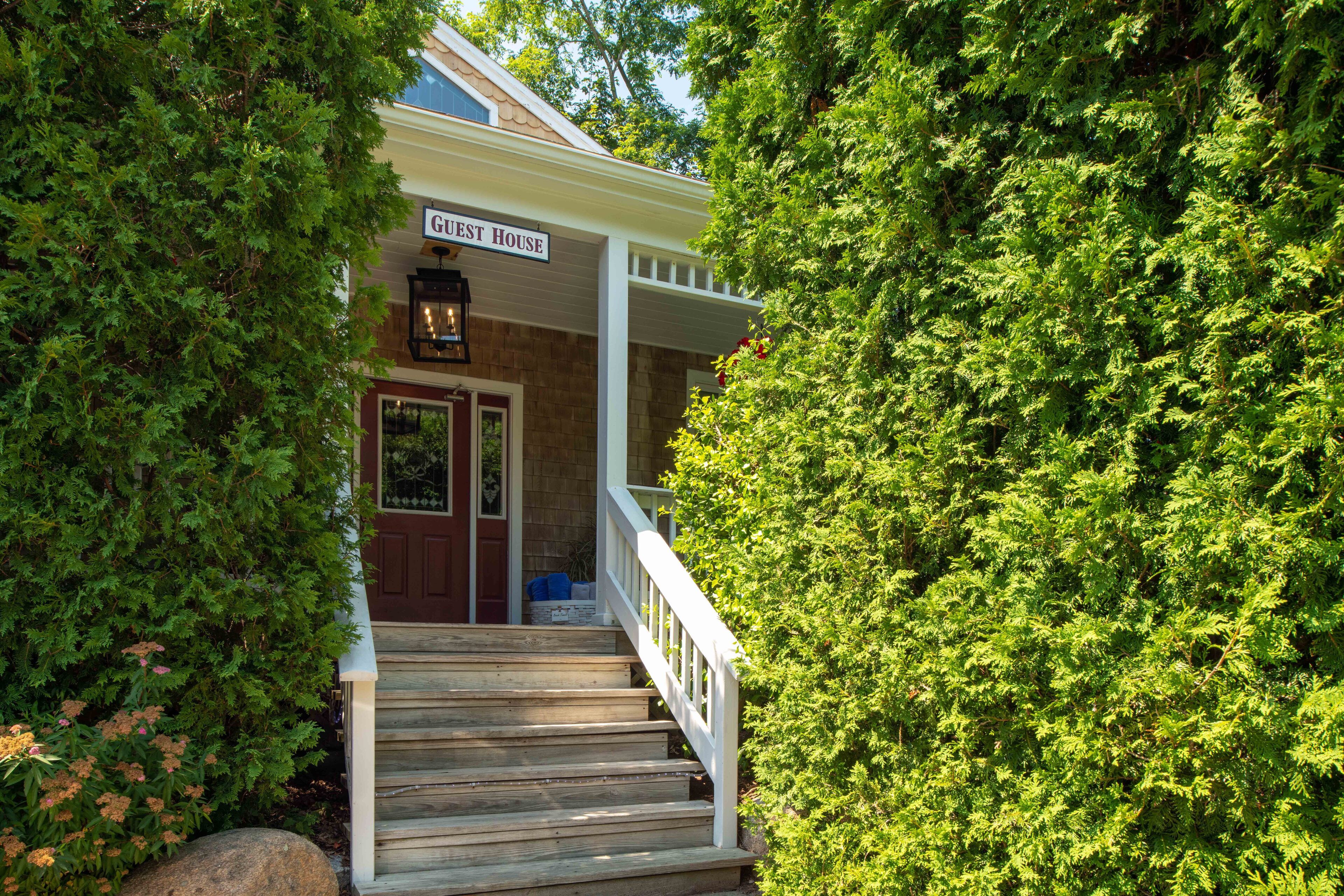 A wooden staircase leading to a porch with a sign reading "Guest House."