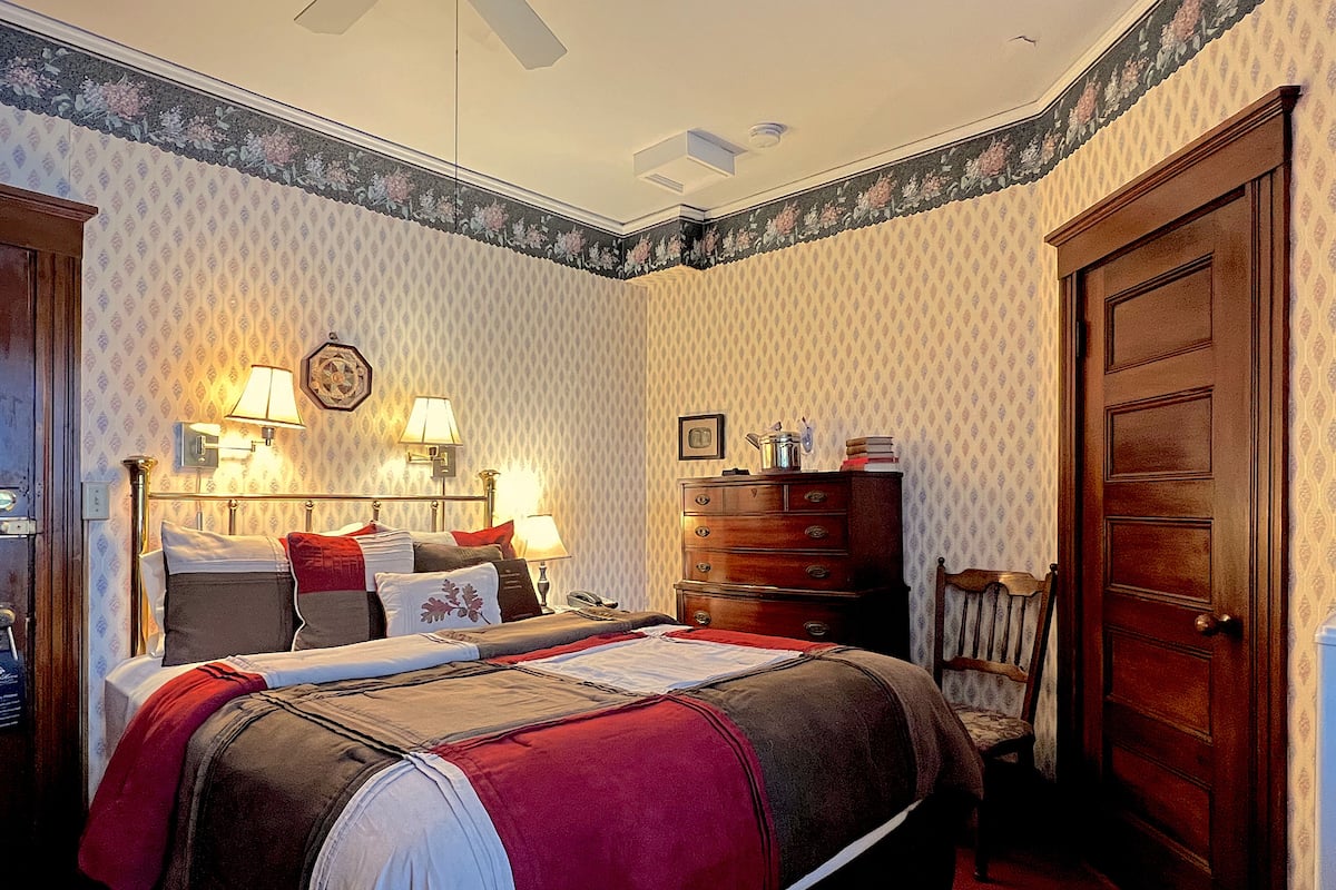 A neatly arranged bedroom with a bed, dresser, and chair.