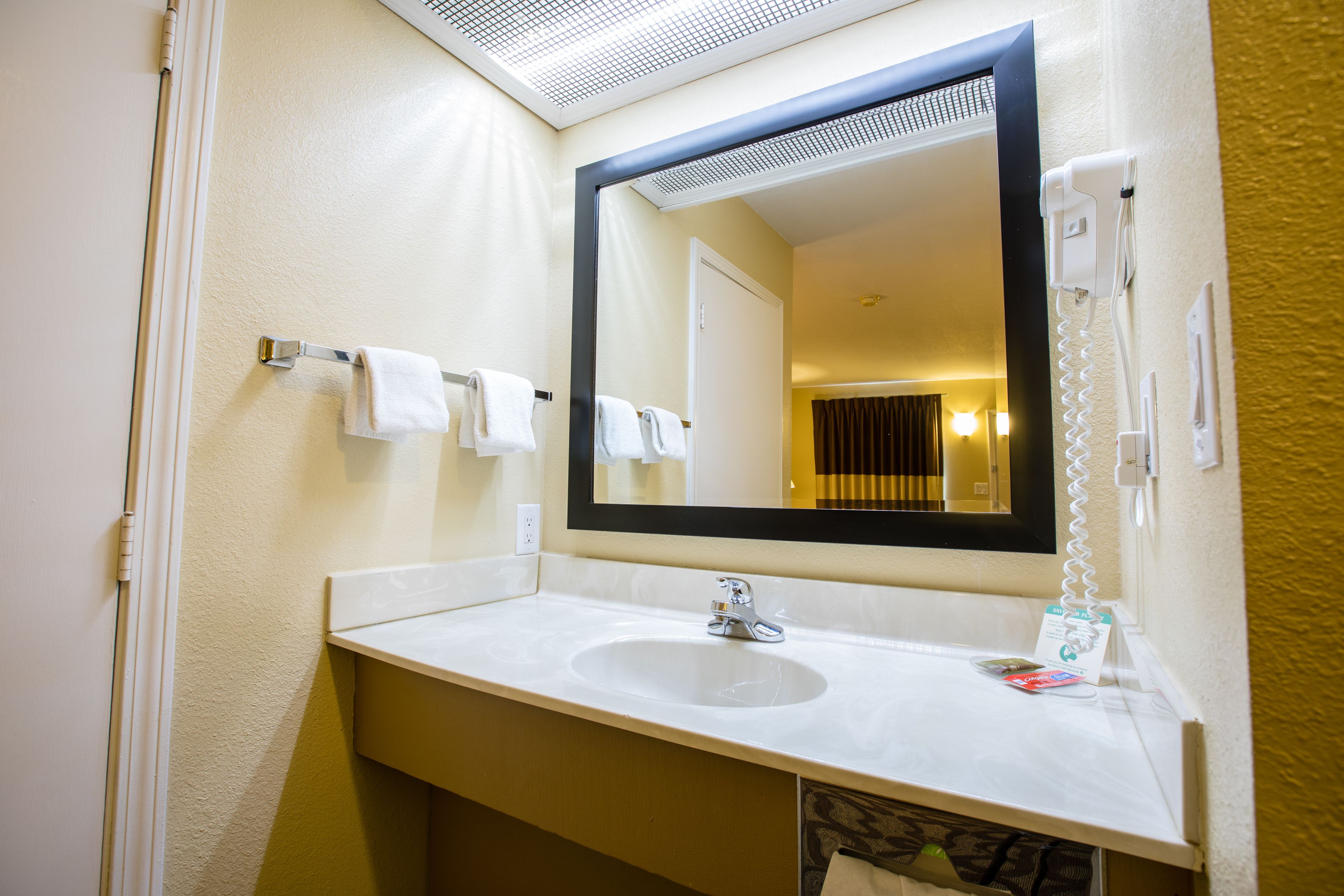 A bathroom with a white sink, a large mirror, and a towel rack.