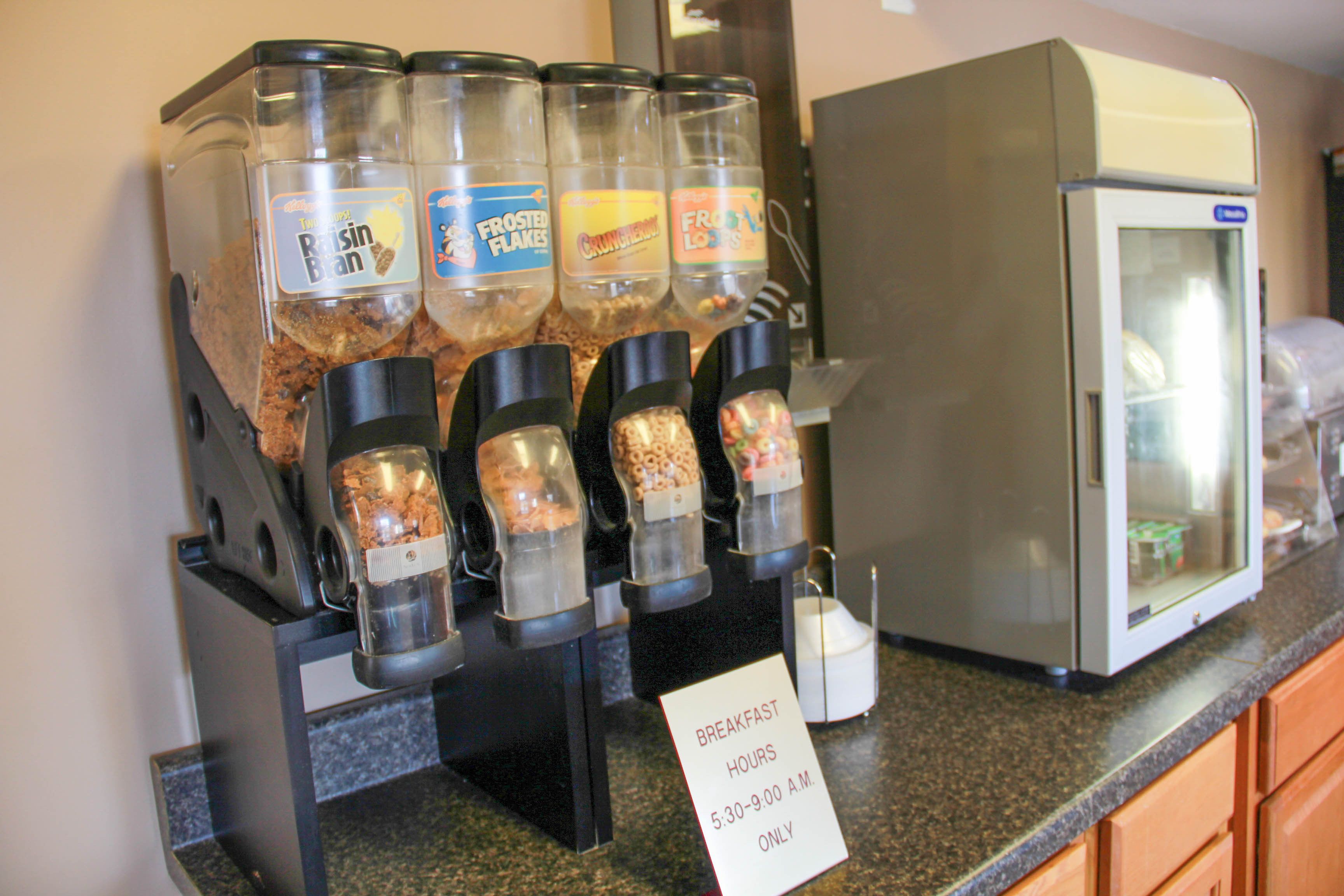 A breakfast bar with various cereal dispensers and a refrigerator.