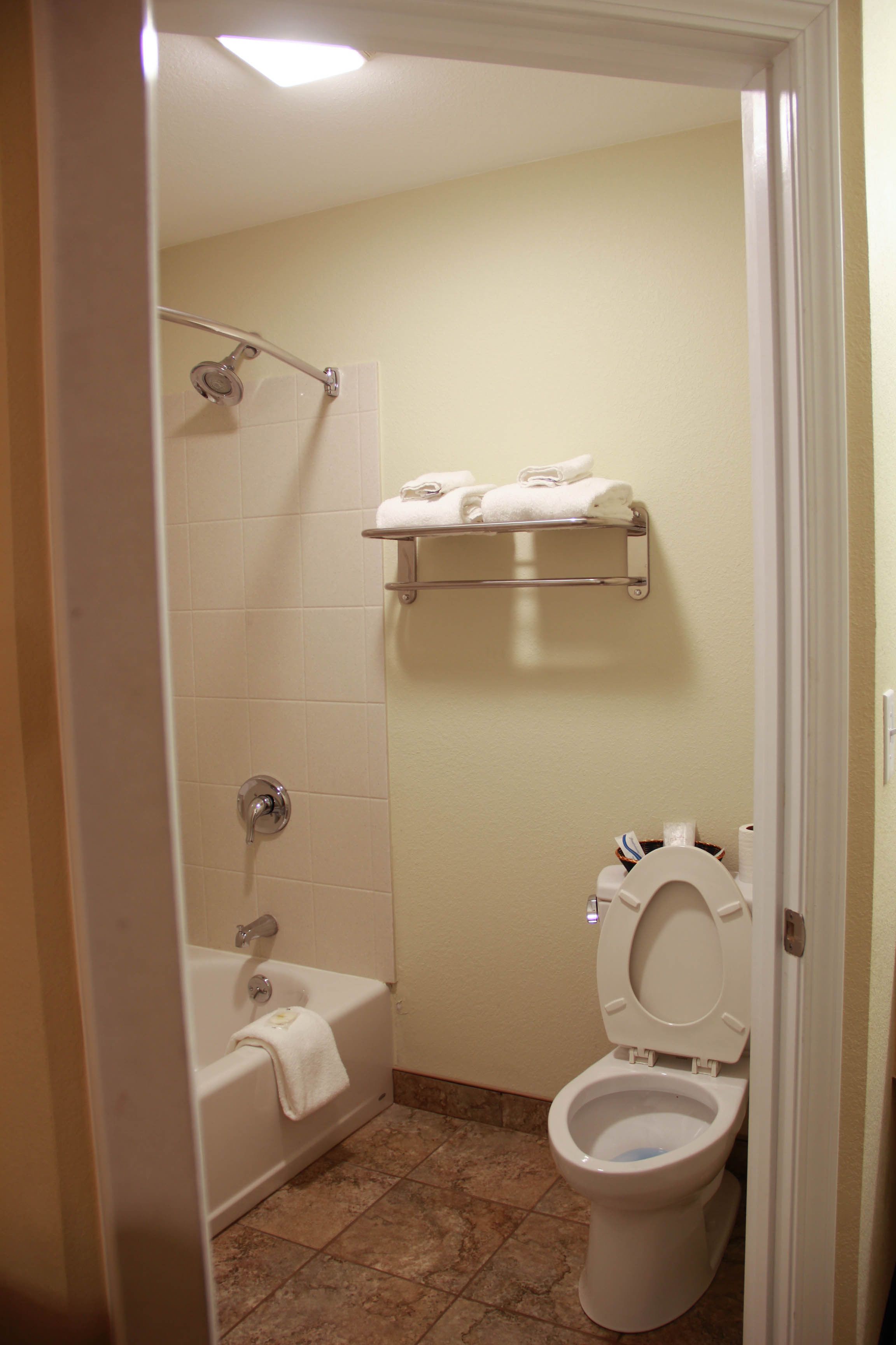 A bathroom with a bathtub, toilet, and a towel rack.
