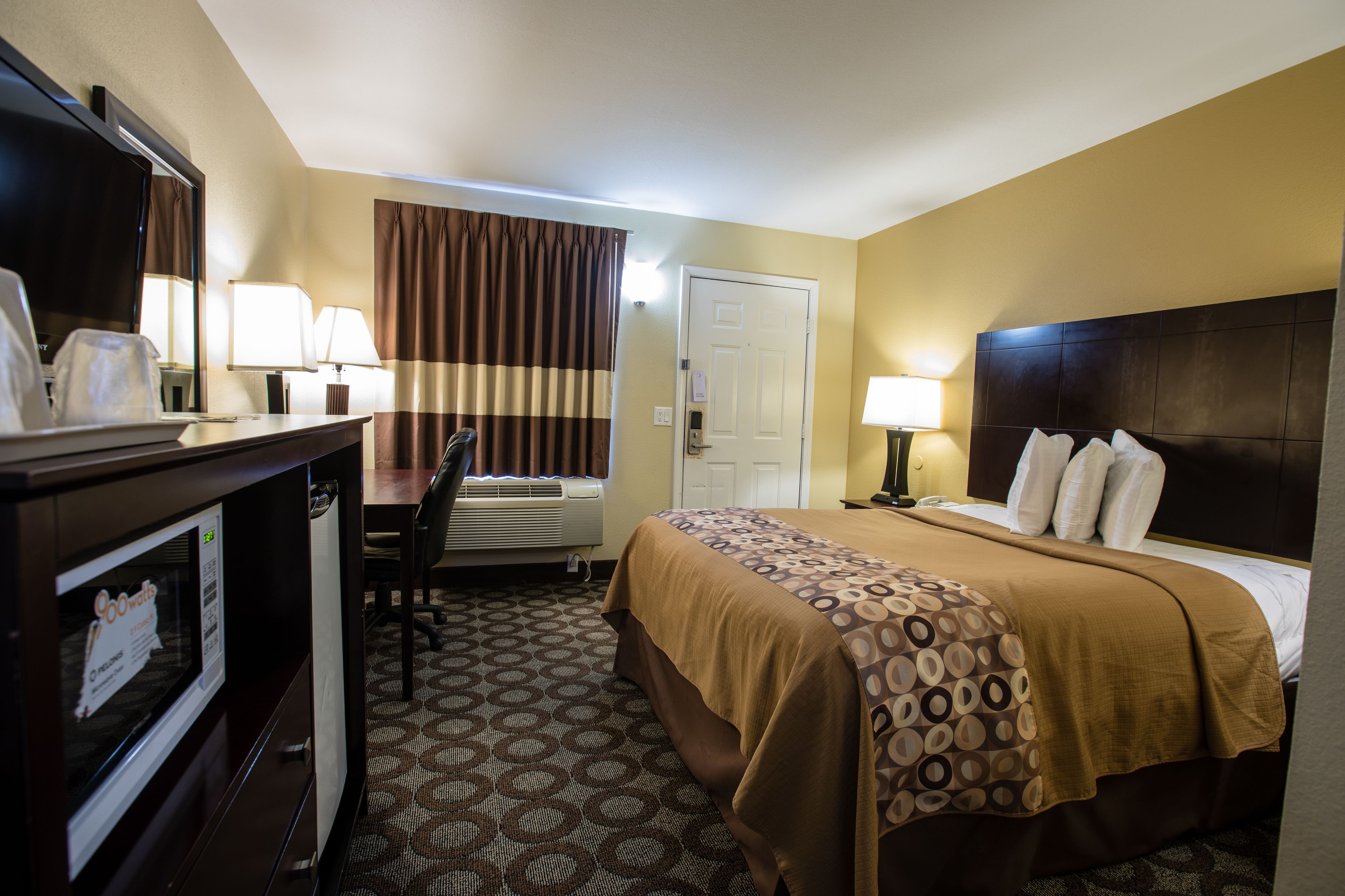 A hotel room with a bed, desk, and chair.