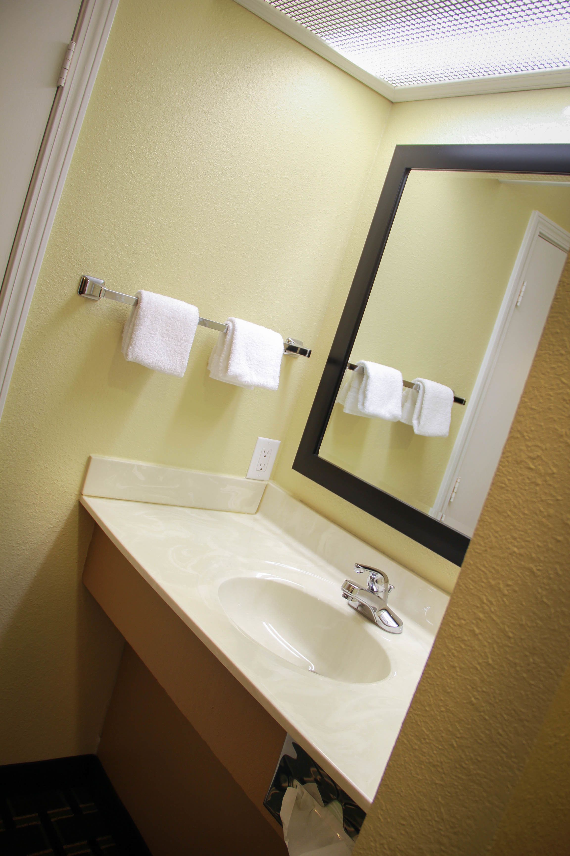 A bathroom with a sink, mirror, and two towels hanging on a towel rack.