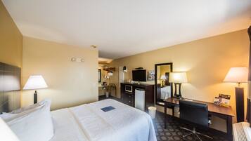 A hotel room with a bed, desk, chair, and a mirror.