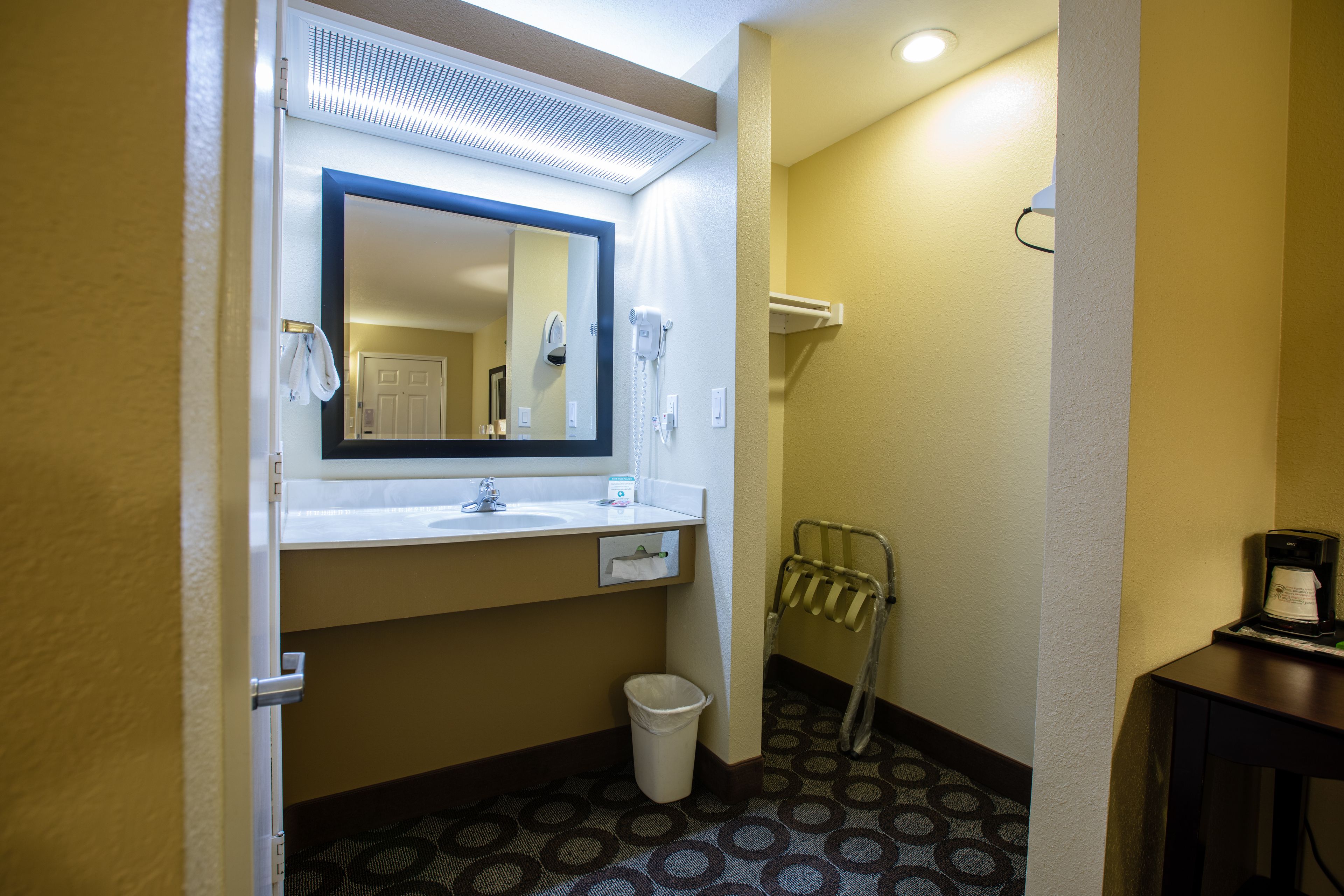 Ein Badezimmer in einem Hotel mit Waschbecken, Spiegel, Handtuchhalter und Mülleimer.