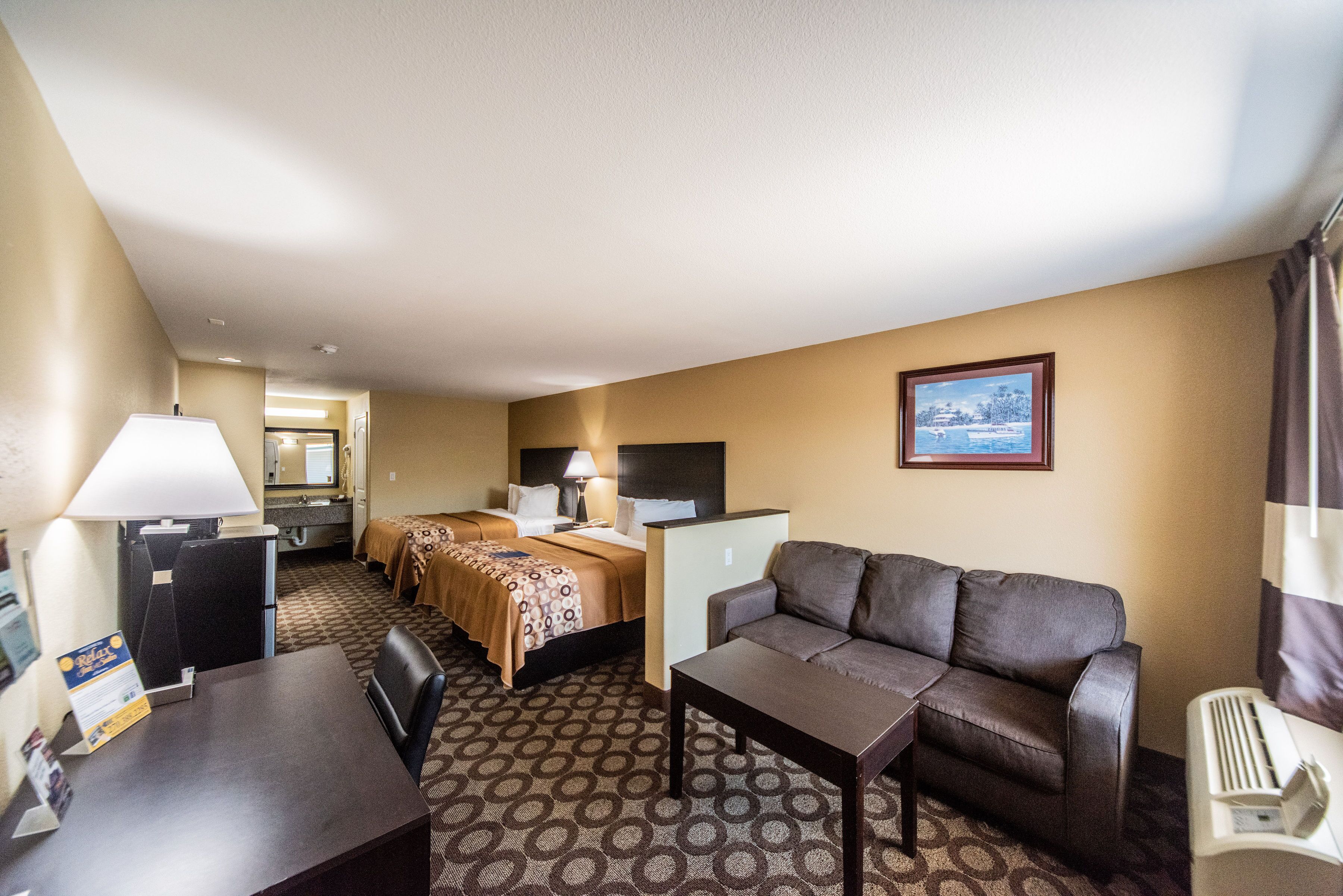 A hotel room with a bed, a sofa, a desk, and a TV.