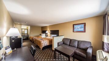 A hotel room with a bed, a sofa, a desk, and a TV.