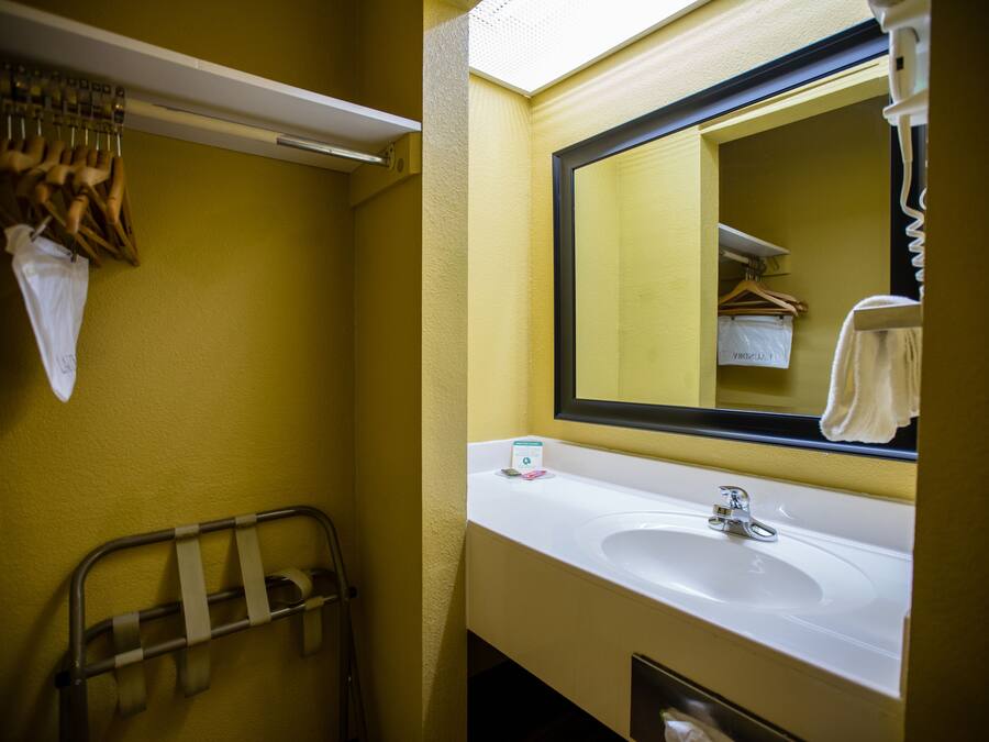 A bathroom with a white sink, a mirror, and a towel rack.