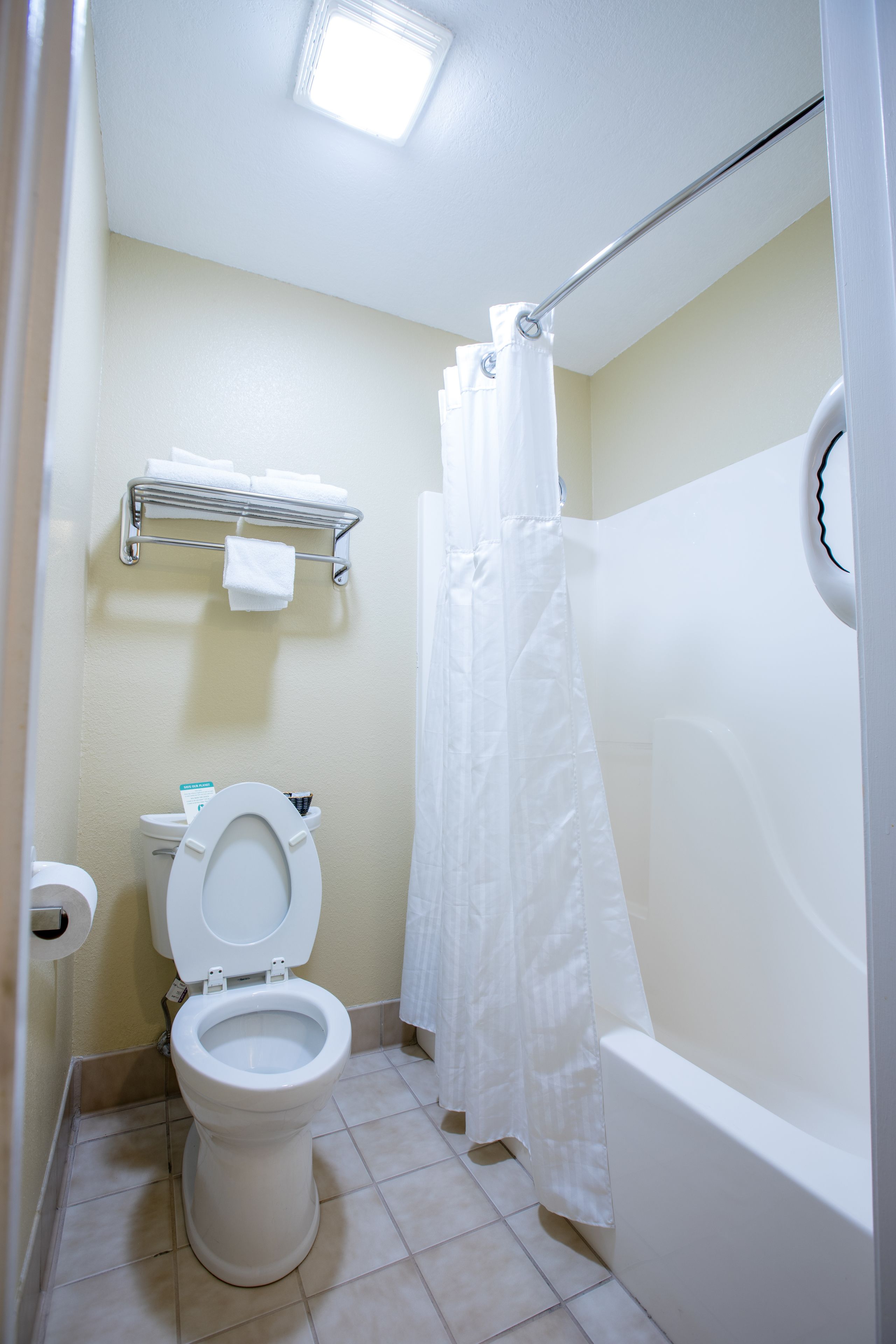 A bathroom with a toilet, a shower curtain, and a bathtub.